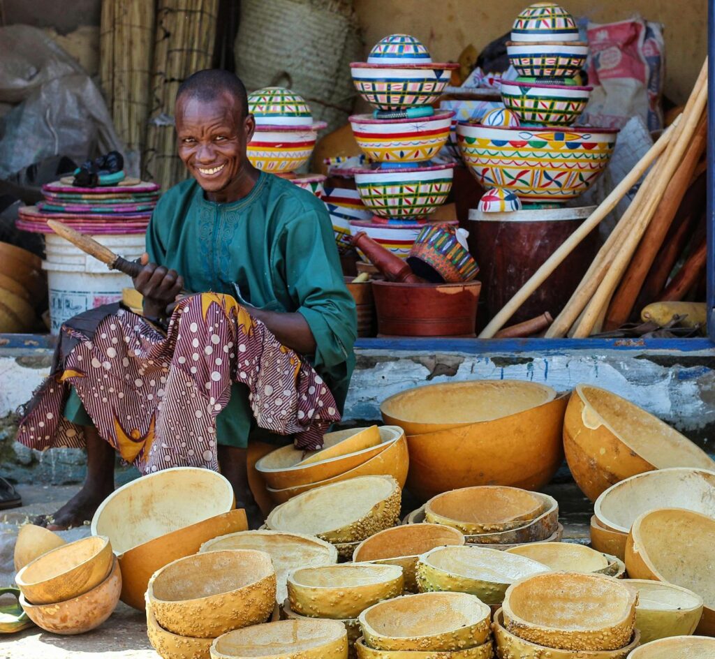 smiling man sitting among stacks of handmade bowls