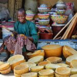 smiling man sitting among stacks of handmade bowls